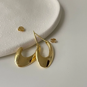 Minimalist 925 sterling silver U-shaped earrings in polished gold on a white stone tray