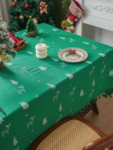 Close-up of green linen Christmas tablecloth with embroidered reindeer and tassel fringe