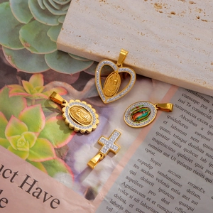 Detailed macro view of 18K gold-plated religious heart and cross charms with rhinestones
