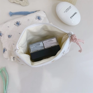 Détail de la mini pochette matelassée avec motif floral bleu et texture en coton doux
