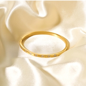 Macro shot of 18k gold plated bangle with sparkling cubic zirconia inlay on silk