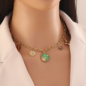 Close-up of golden necklace with green circular charm and celestial sun star pendants