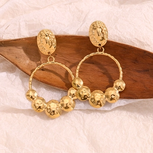 Detail shot of 18K gold-plated hammered texture earrings on organic background