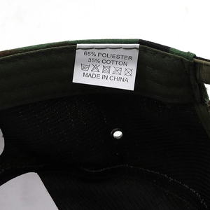 Detail view of the camouflage flat cap showing breathable mesh and material label