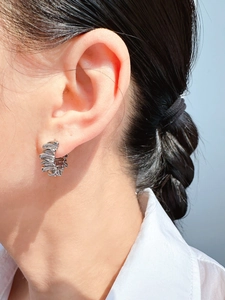 Close-up of silver textured layered hoop earring worn on model for a modern fashion look