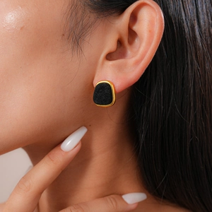 Close-up of vintage gold rimmed black flocked geometric earring on model ear