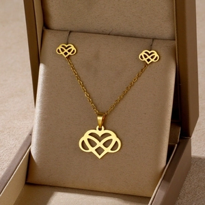 Detailed view of golden heart-infinity necklace and earring set in a velvet gift box