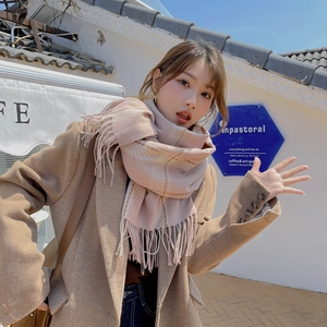 Woman wearing a beige checkered cashmere-feel scarf with fringes and camel coat