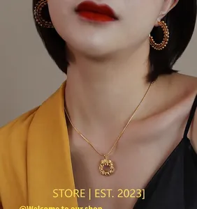 Close-up of a 18k gold plated textured pendant necklace and beaded hoop earrings on model