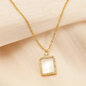 Detailed macro of gold square pendant with zircon inlay and white shell texture