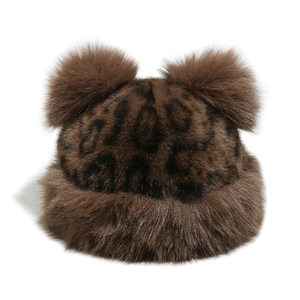 Macro shot of faux fur winter hat with leopard print pattern and plush bear ear pom-poms