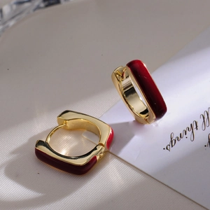 Macro shot of gold square leverback earrings with elegant deep red enamel finish