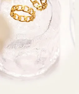 Gros plan sur des bagues à maillons cubains plaqués or 18 carats sur du verre