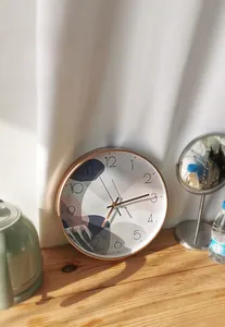Close-up of a silent plastic wall clock with rose gold frame and abstract art dial