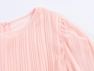Detail of round neckline and pleated chiffon fabric texture on pink long-sleeved dress