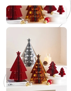 Close-up of colorful accordion-style paper Christmas trees with star toppers on a cozy desk