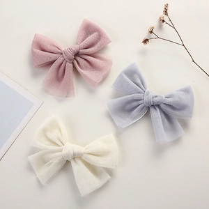 Three delicate tulle bow hair clips in pink, light blue, and beige colors