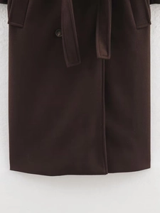 Detailed view of dark brown wool coat showing waist belt buckle and fabric texture