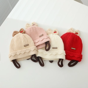 Détail de quatre bonnets en tricot pour bébé avec nœuds cerise et jolies tresses