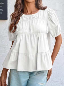 Detailed view of white tiered smocked top with textured gathering and puff sleeves