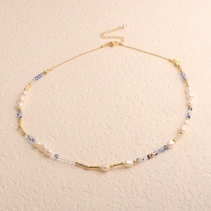 Detailed view of baroque pearls with blue beads and golden accents on a cream background