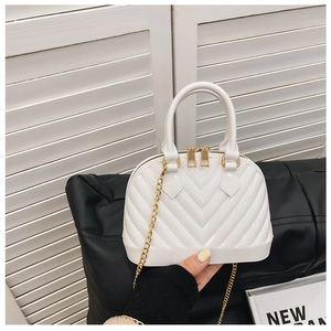 Detail of white shell-shaped jelly bag featuring gold hardware and metallic chain strap