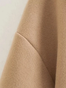 Macro view of camel wool fabric texture and fine stitching on the long trench coat