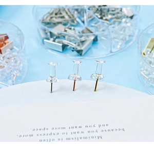 Macro shot of clear push pins with gold and rose gold tips in a blue office setting