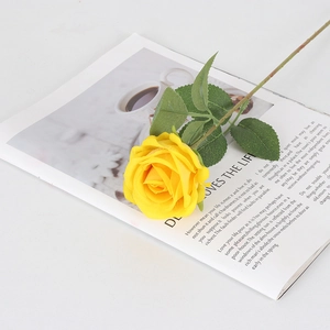 Rosa de terciopelo amarilla artificial sobre revista para decoración de bodas