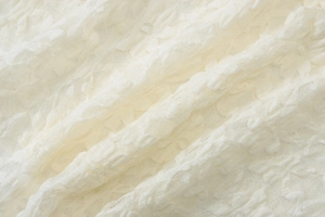 Macro shot of off-white lace fabric detail with intricate texture and soft knit patterns