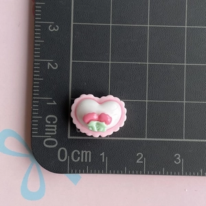 Macro shot of 1.5cm heart resin charm with cherry detail on a black scale mat