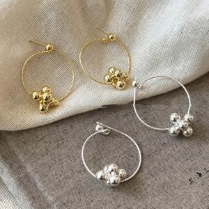 Detailed view of silver and gold twisted hoop earrings with beaded cluster accents