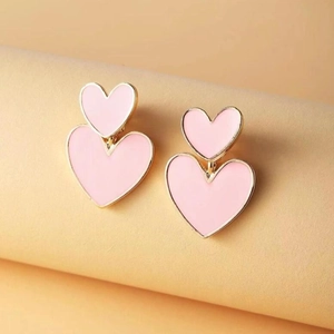 Detail view of pink heart earrings with gold trim on elegant pastel pedestal