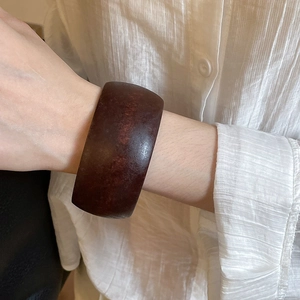 Detailed view of a wide brownish resin bangle with natural texture on a wrist