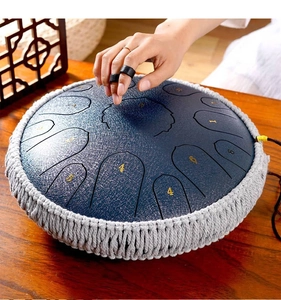 Macro shot of playing a navy steel tongue drum with finger picks on wooden table