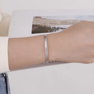 Gros plan détaillé d'un bracelet manchette argenté torsadé porté par un mannequin