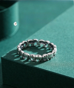 Macro shot of 925 sterling silver elephant ring on a textured dark green surface