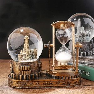 Close-up of retro hourglass with crystal ball and Eiffel Tower model on bronze metal base