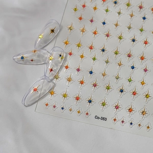 Detailed macro view of 3D gold starburst nail stickers with colorful gemstone centers