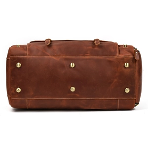 Detail view of leather travel bag base with six gold protective metal feet and stitching