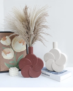 Macro view of matte ceramic petal vases in terracotta and white with reed decor