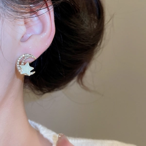 Close-up of elegant star and moon earrings with gold plating and white rhinestones