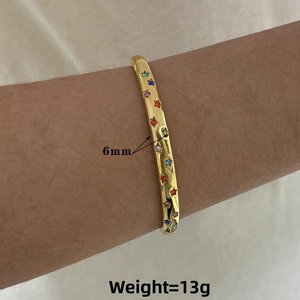 Detail of 6mm gold-toned stainless steel cuff bracelet with colorful star-shaped gemstones