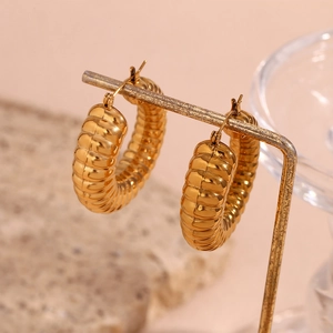 Macro detail of 18K gold plated stainless steel lava earrings with spiral texture