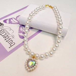 Detail of single strand pearl pet necklace with a crystal heart pendant on decorative card