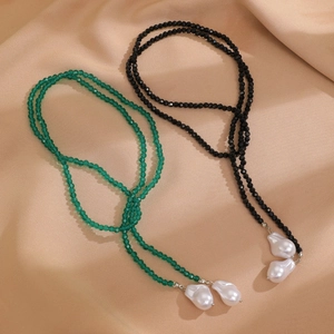 Detailed macro view of baroque pearl necklaces in green and black on silk fabric