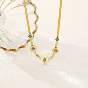 Gold snake chain necklace with three round turquoise sunburst pendants on white background
