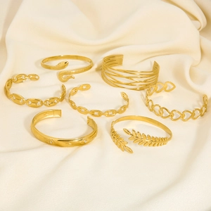 Detailed close-up of a 7-piece gold hollow heart and snake pattern bangle set on satin