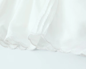 Gros plan d'un chemisier blanc avec broderie délicate et bordure en dentelle festonnée