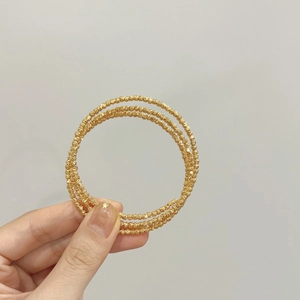 Bracelet multi-rangs minimaliste plaqué or avec perles sur une main de femme